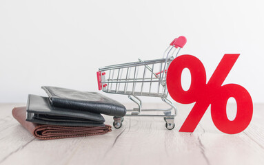 Wall Mural - Shopping cart from the supermarket and sign percent with leather wallet on white wood background. Shopping in the Mall, shop, shopping, a large selection. big sale