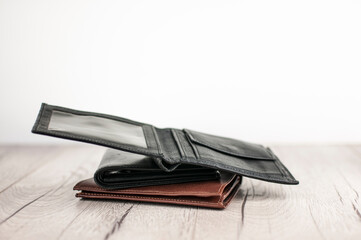 open leather wallet on stacks of leather wallets over white wood background