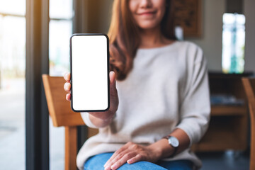 Poster - Mockup image of a beautiful asian woman holding and showing a mobile phone with blank white screen