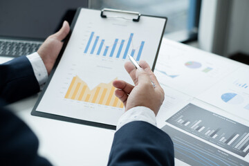 The businessman hand sits at their desks and calculates financial graphs showing the results of their investments planning the process of successful business growth