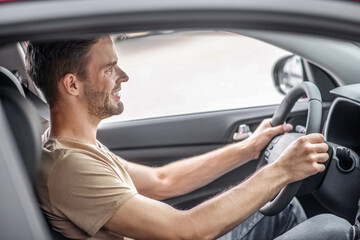 Wall Mural - Young male sitting in car, holding steering wheel