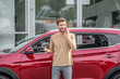 © zinkevych - Young bearded male talking on smartphone in front of red car