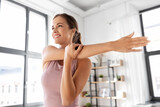 sport, fitness and healthy lifestyle concept - smiling young woman stretching arm at home