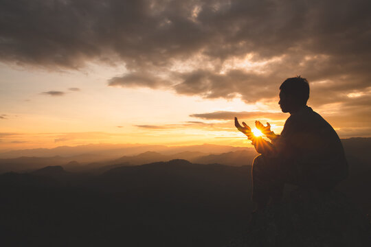 Silhouette of young  man hands open palm up worship and praying to god  at sunrise, Christian Religion concept background.