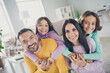 © deagreez - Photo of full family four people parents hold piggy back kids wear colorful sweater in living room indoors