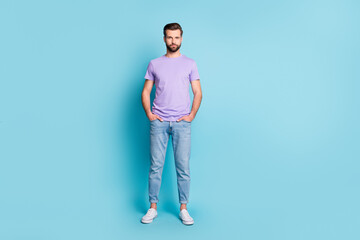 Wall Mural - Full length photo of young serious man confident hands in pocket isolated over blue color background