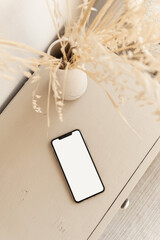 Wall Mural - Blank screen smart phone on beige pastel table. Flat lay, top view. Copy space mockup template.