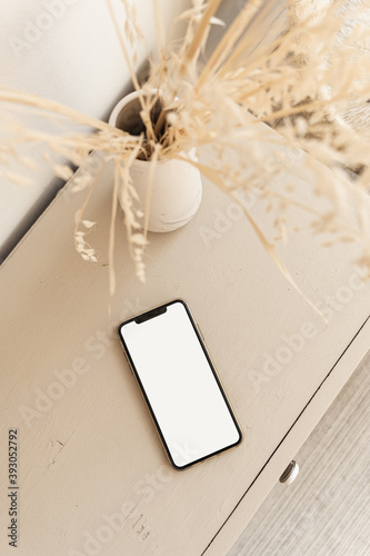 Blank screen smart phone on beige pastel table. Flat lay, top view. Copy space mockup template.