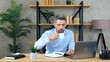 © viacheslav - Business man drinking coffee tea listens employee remote online video call conference web cam meeting chat. Bearded male in home office wears wireless earphones uses laptop computer