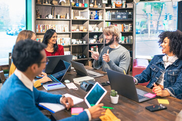 Wall Mural - Team of young multi ethnic creatives satisfied with successful results, blond man points fingers in positive and happy to his team, concept of positive collaboration, brainstorming, diversity