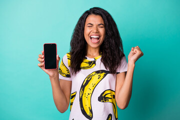 Wall Mural - Photo of pretty excited lady hold telephone screen empty space closed eyes wear banana print t-shirt isolated teal color background