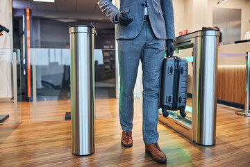 Wall Mural - Male entering an open swing turnstile while carrying a case