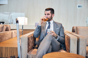 Wall Mural - Business professional swallowing some whisky while working on a phone