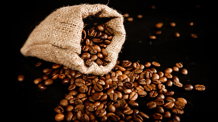 Poster - High angle shot of coffee beans on a sack bag isolated on black background