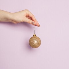 Wall Mural - Gold Christmas balls decoration in woman hand on lilac card background