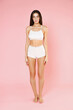 © ViDi Studio - Full length of attractive beautiful fitness young brunette woman in white underwear showing fit sports body posing standing looking camera isolated on pastel pink colour background, studio portrait.