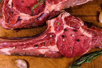 Raw ribeye steak, spices and rosemary on cutting board. Top view