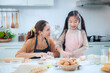 © pornchai - Happy Asian mother and adorable daughter helping knead the dough to make a bakery in the kitchen.