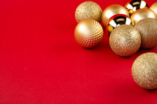 Many Golden Christmas Baubles And Glitter On Red Backdrop. Selective Focus - Shallow Depth Of Field.