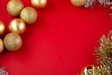 Many Golden Christmas Baubles And Glitter On Red Backdrop. Selective Focus - Shallow Depth Of Field.