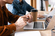 © LIGHTFIELD STUDIOS - Cropped view of man with pen looking at blank screen of laptop, while sitting at workplace with blurred woman on background