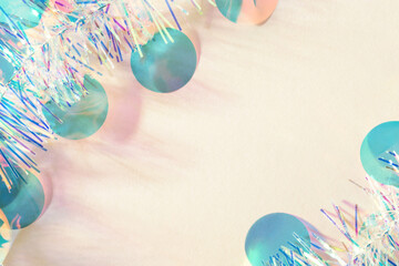 Wall Mural - christmas tinsel garland and confetti on beige background. new year frame, copy space, flat lay.