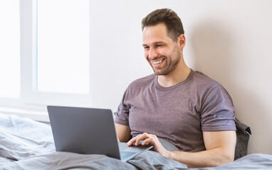 Aufkleber - Cheerful Guy Using Laptop Working Online Remotely Sitting In Bedroom