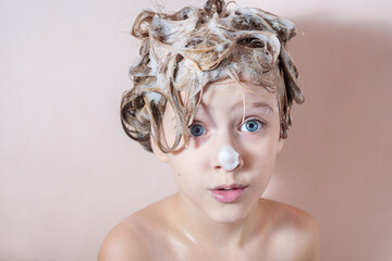 Wall Mural - a little blonde girl washes her hair in the shower with foam on her hair and nose. playing in the ba