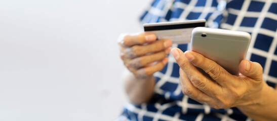 close up senior woman hand using smartphone and holding credit card to paying bills from shopping online concept	
