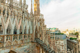 Fototapeta Paryż - Roof of Milan Cathedral Duomo di Milano with Gothic spires and white marble statues. Top tourist attraction on piazza in Milan, Lombardia, Italy. Wide angle view of old Gothic architecture and art.