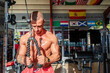 © Javier De La Torre/ADDICTIVE STOCK - Powerful male athlete with sweaty naked torso pulling ropes of cable machine and pumping biceps while training in modern gym