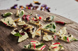 © Iombi Garcia/ADDICTIVE STOCK - Top view of pieces of tasty chocolate with various flower petals and herbs placed on wooden table