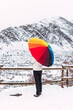 © Galdric Penarroja/ADDICTIVE STOCK - Side view of anonymous person standing under colorful umbrella and enjoying amazing view of Pyrenees mountain ridge covered with snow in winter