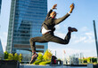 © Jose Carlos Cerdeno/ADDICTIVE STOCK - Side view of carefree black male entrepreneur in classy suit and with smartphone jumping on street in downtown and looking away