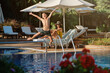 © Philippe Degroote/ADDICTIVE STOCK - Cheerful boy having fun and jumping into swimming pool while mother resting on lounge chair at poolside during  summer vacation together in resort