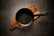 © Philippe Degroote/ADDICTIVE STOCK - Top view of metal frying pan placed on wooden cutting board on table in kitchen