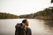 © Maskot - Rear view of man with backpack looking away against lake in forest