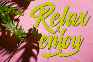 Wall Mural - top view of fresh tropical green leaves on pink plastic background with relax and enjoy illustration