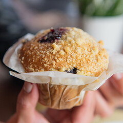 cupcake wrapped in paper and held by the hands of a woman.ARW