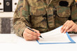 © cunaplus - Close up of executive military man hands signing contract on a desk at work