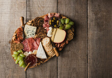 Top View Of Charcuterie Board Of Meat, Cheese, Crackers On Wood Table.