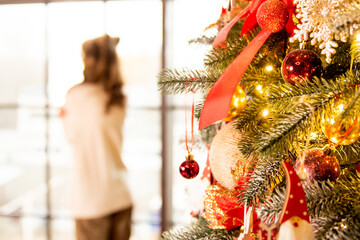 Decorated Christmas tree with red balls. On the background silhouette of a girl in warm sweater.