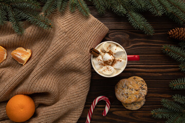 On a table decorated with Christmas decor, there is a cup of hot chocolate and holiday cookies