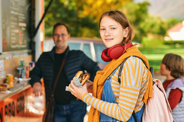 Family eating hamburgers next to food truck, street food concept