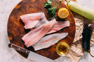 Fillet of rainbow trout with spices and herbs, lemon, tomato and olive oil with a kitchen knife.