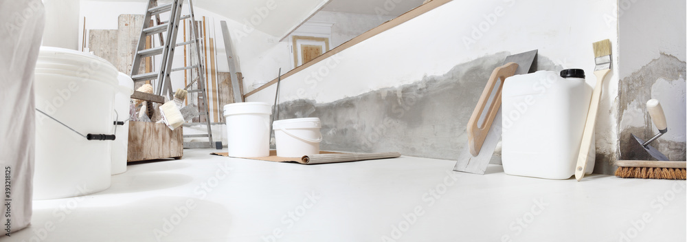 Low angle of indoor shot of construction or building site of home renovation with tools on white floor with paint buckets and primer jerry can - obrazy, fototapety, plakaty 