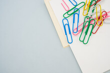 Closeup Shot Of A Blank Paper With Colorful Paper Clips On A Light Green Background