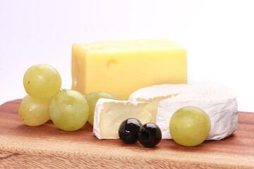 Closeup shot of two types of cheese and grapes on a chopping board isolated on a white background