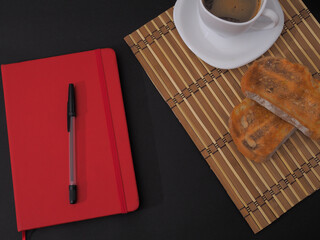 Wall Mural - Closeup shot of a red notebook for text with a pen and a cup of coffee