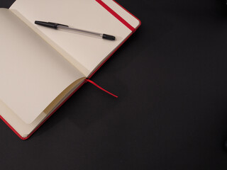 Canvas Print - Closeup shot of an open and empty notebook for text with a pen isolated on dark background